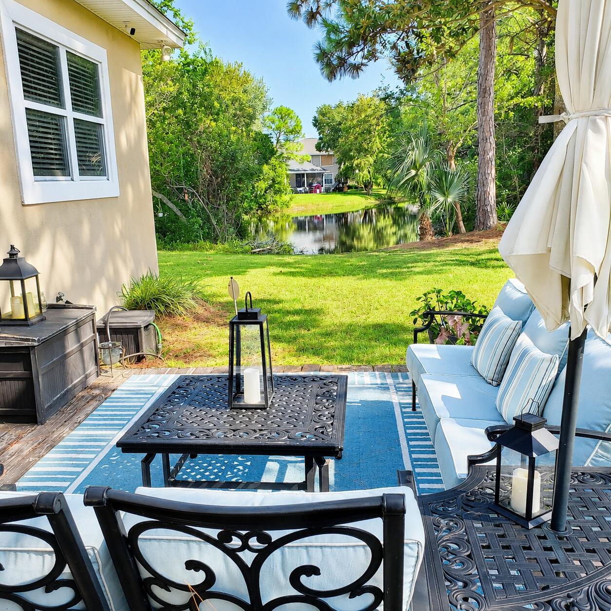 Furnished patio with blue seating overlooking a landscaped lawn and pond.