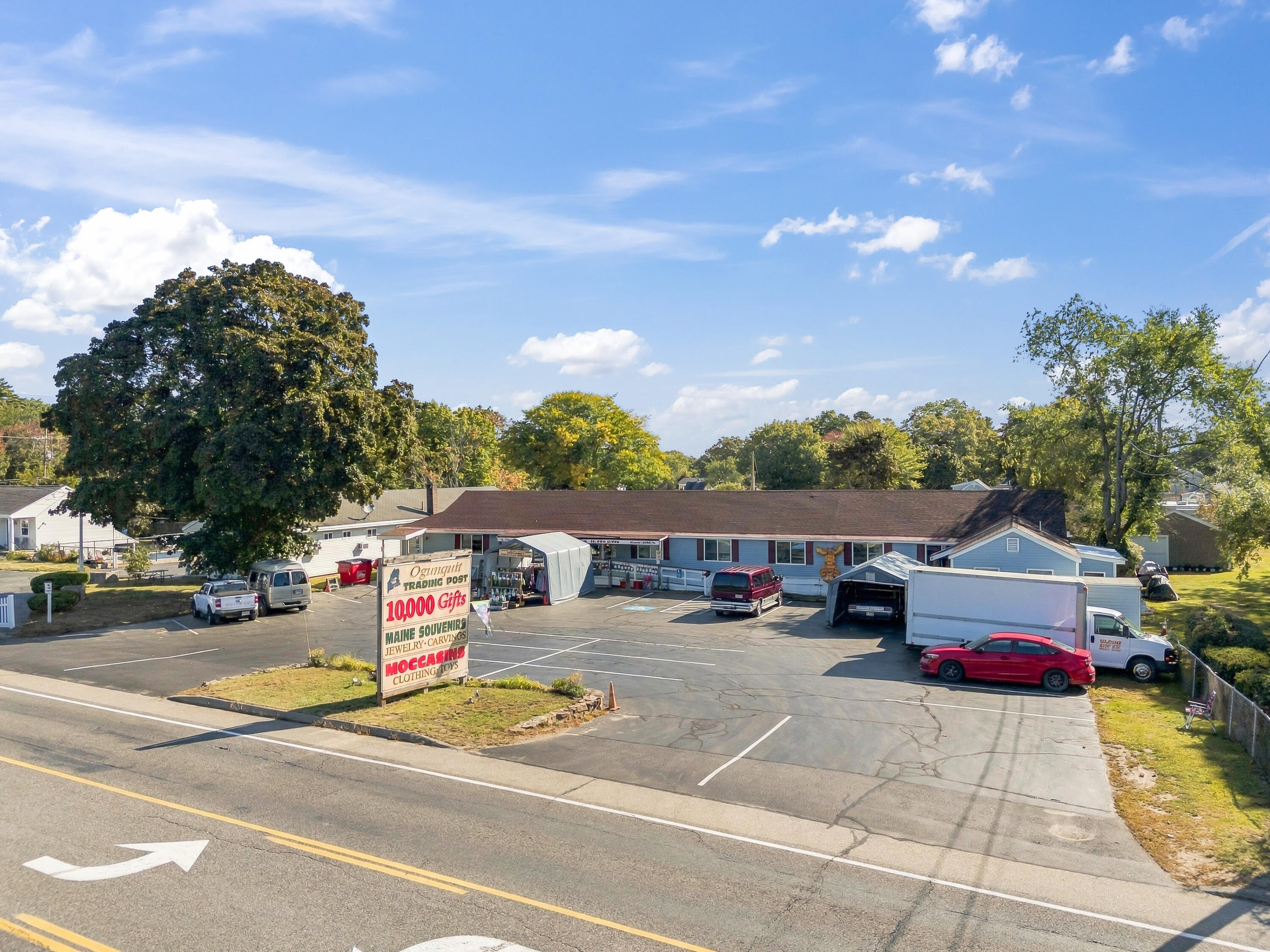 Commercial building and parking lot with an Ogunquit Trading Post roadside sign.