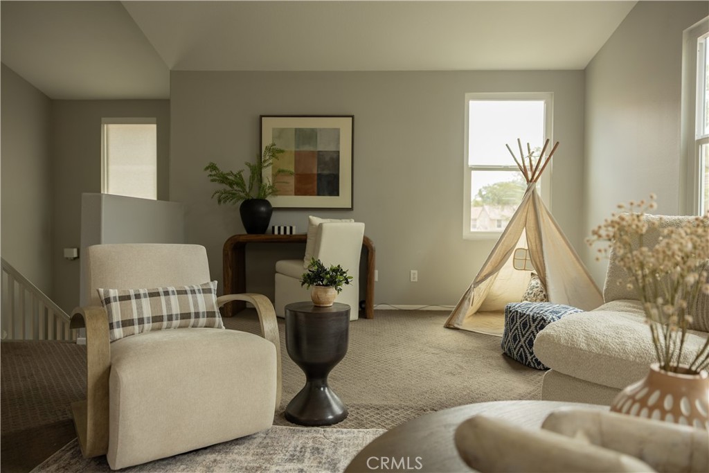 Staged sitting area with a small teepee beside the windows and a stair railing.