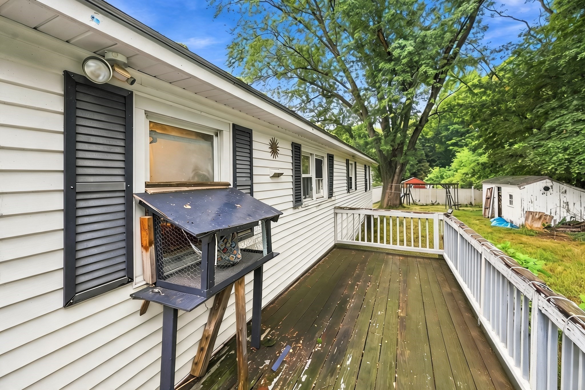Side deck of 21 Cranton Avenue with weathered boards, white siding, and a shaded backyard.