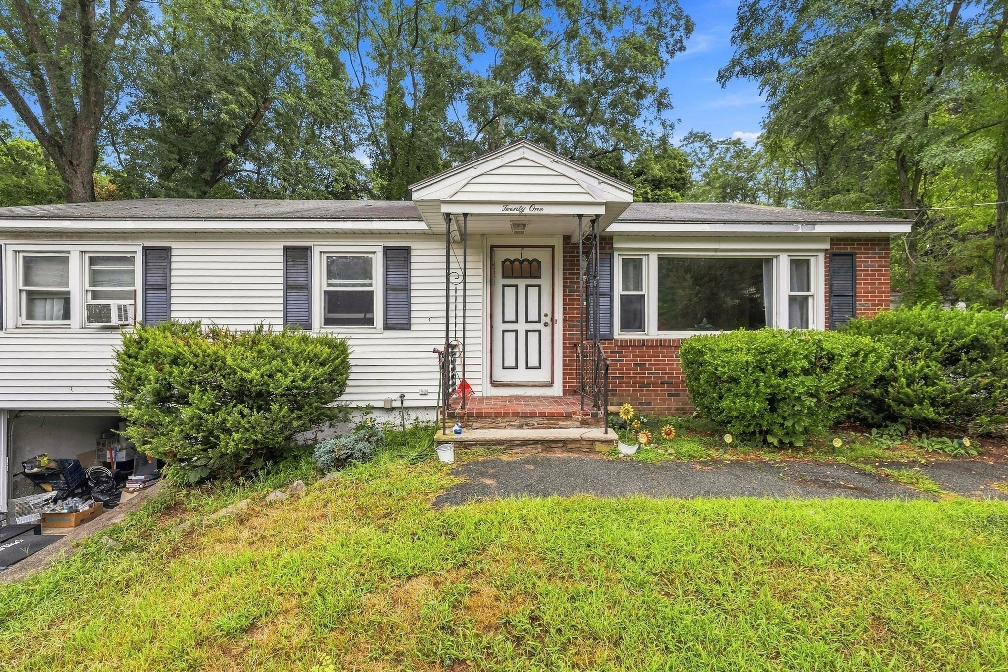 Ranch-style home with white siding, brick accents, covered entry, and an open garage.
