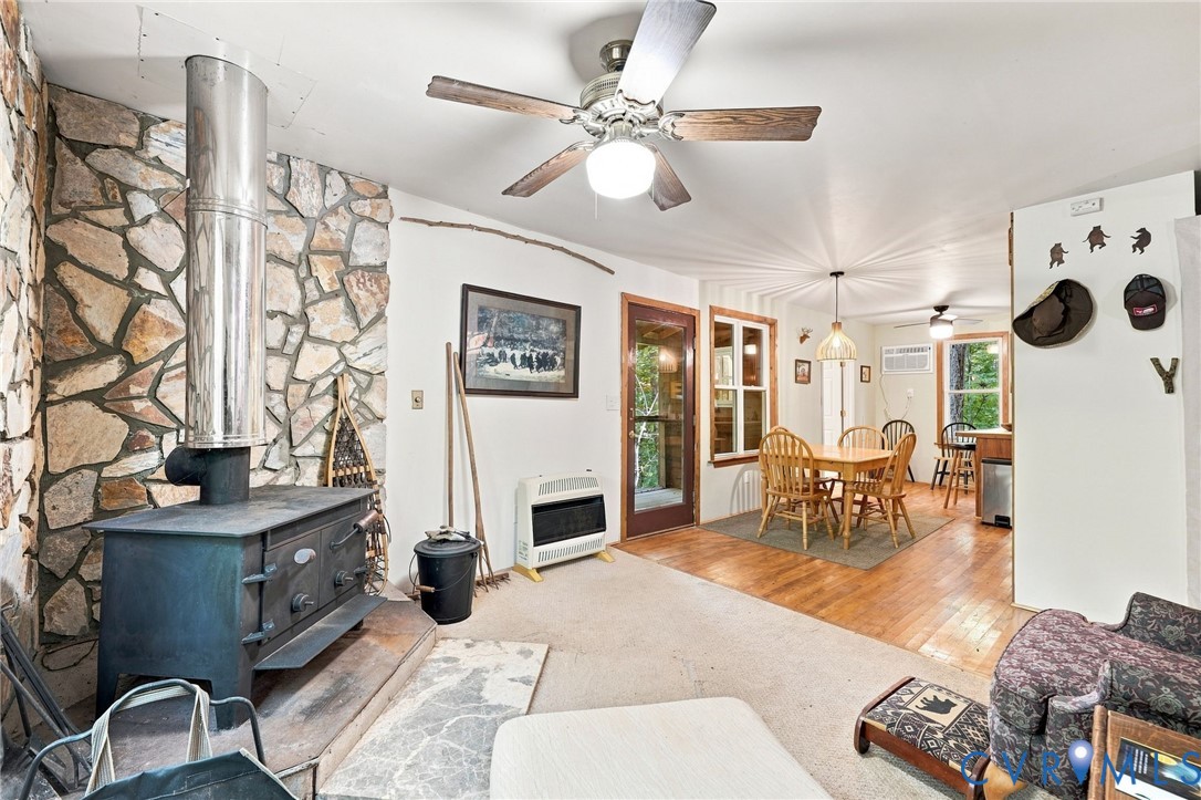 Living and dining area with a stone hearth, wood-burning stove, and wood floors.