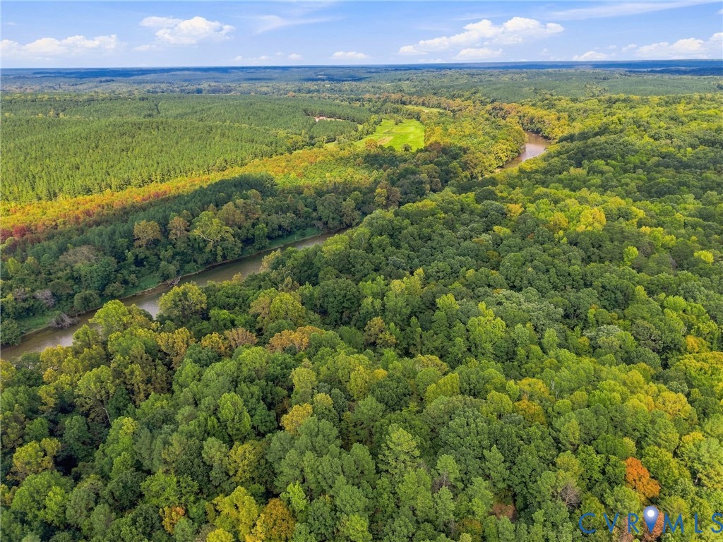 Aerial view of wooded land with a winding river and a small clearing.