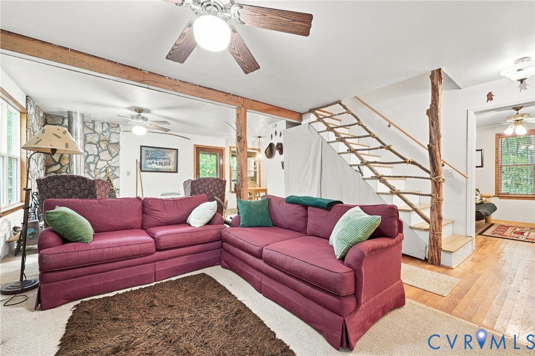 Living room with burgundy sectional, stone accent wall, and open rustic staircase.
