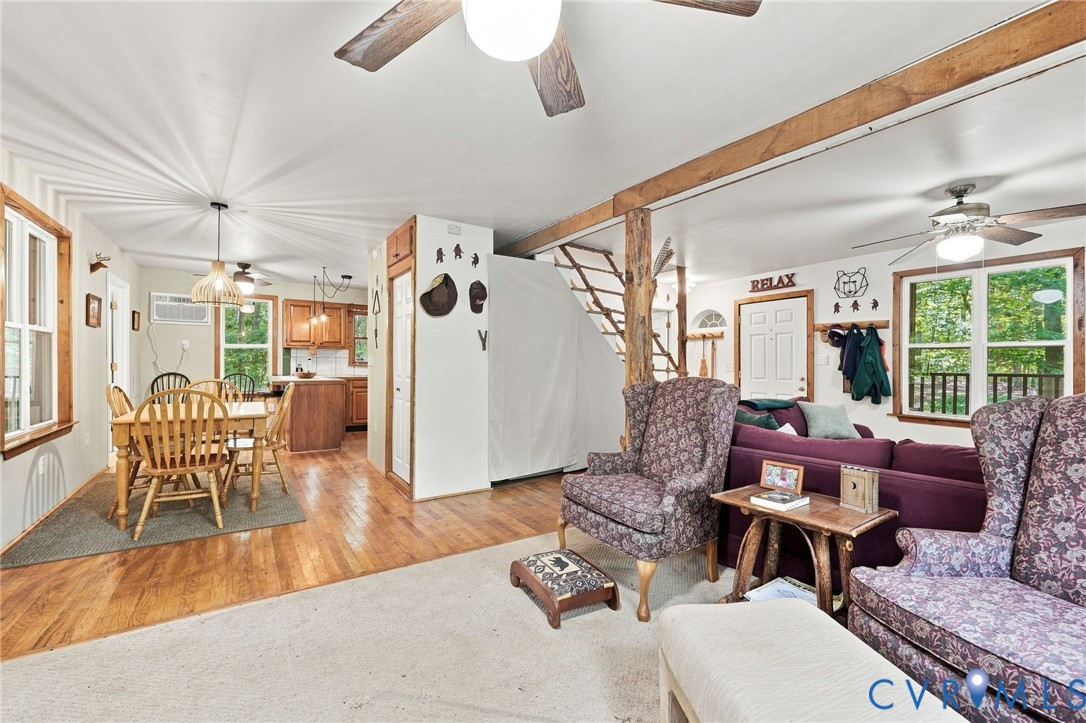 Open-plan living and dining area with exposed timber beams, hardwood floors, and views of trees.