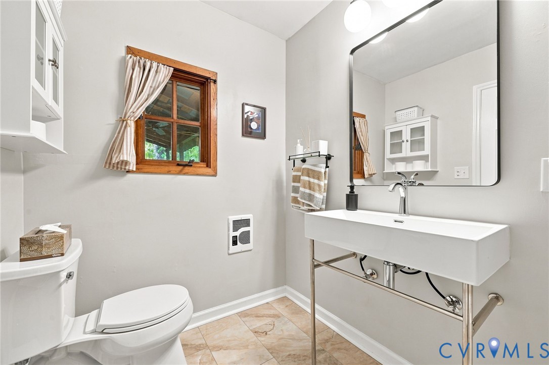 Bathroom with a white framed sink, large mirror, and wood-trimmed window.