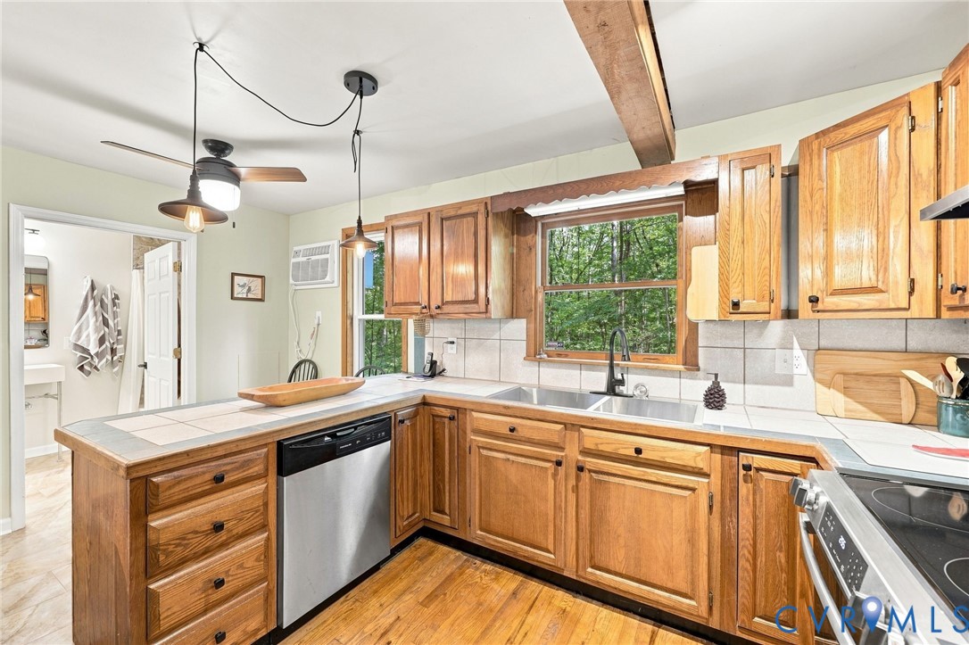 Kitchen with wood cabinets, stainless steel appliances, and a sink overlooking trees through the window.