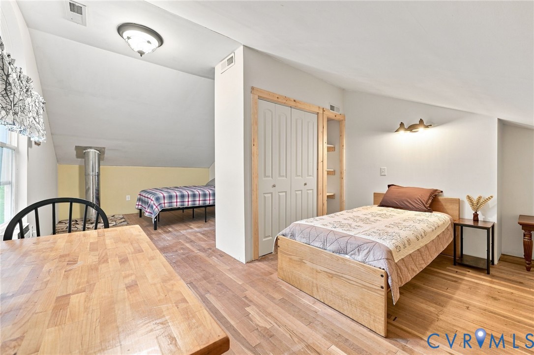 Furnished bedroom with a wood bed, sloped ceiling, and a second bed in the adjoining loft area.