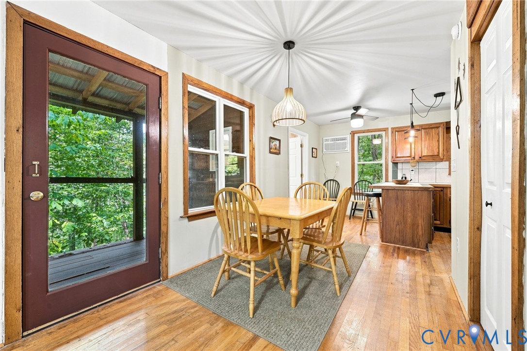 Dining area with a wooden table, hardwood floors, and a kitchen island beside a glass door.