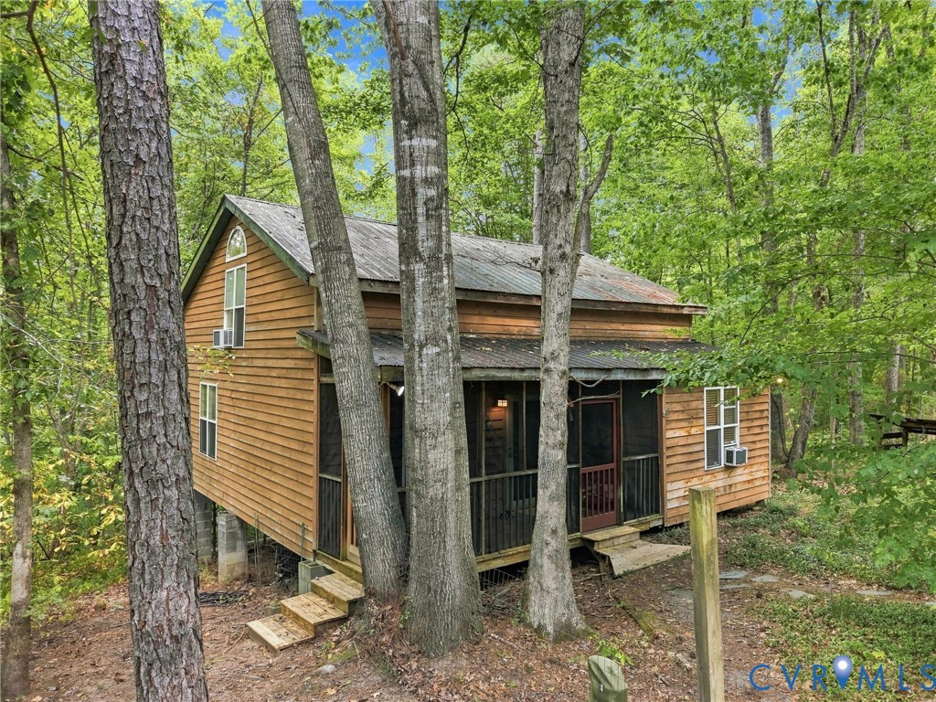 Wood-sided home with a screened porch nestled among leafy trees.