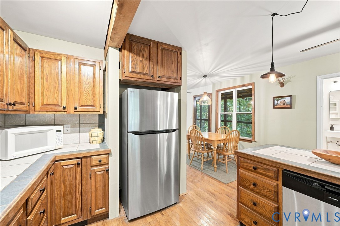Kitchen with oak cabinetry and tiled counters opening to a window-side dining area.