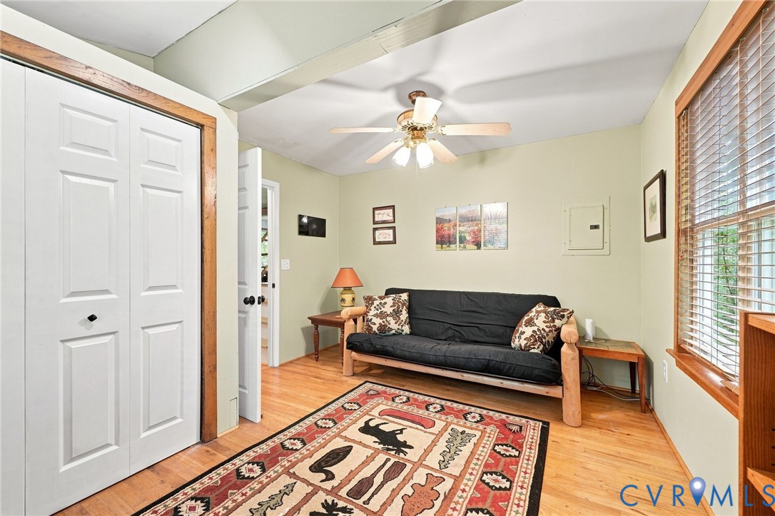 Living room with a black sofa, patterned rug, and large window with wooden blinds.
