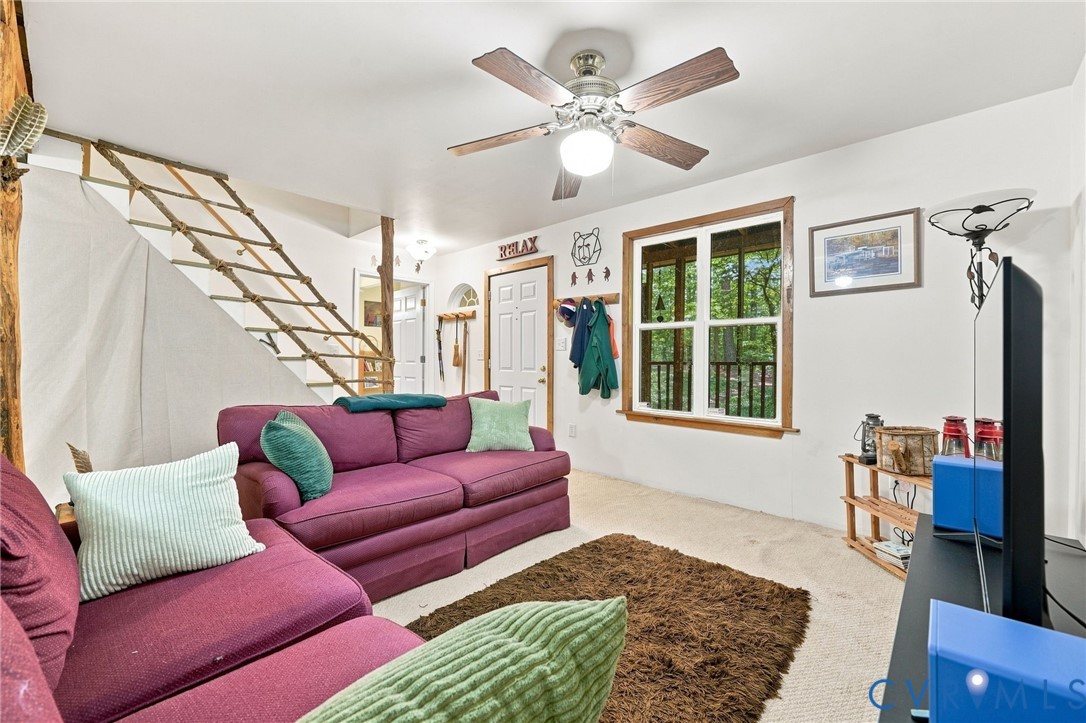 Living room with a magenta sectional, rustic open staircase, and window overlooking trees.