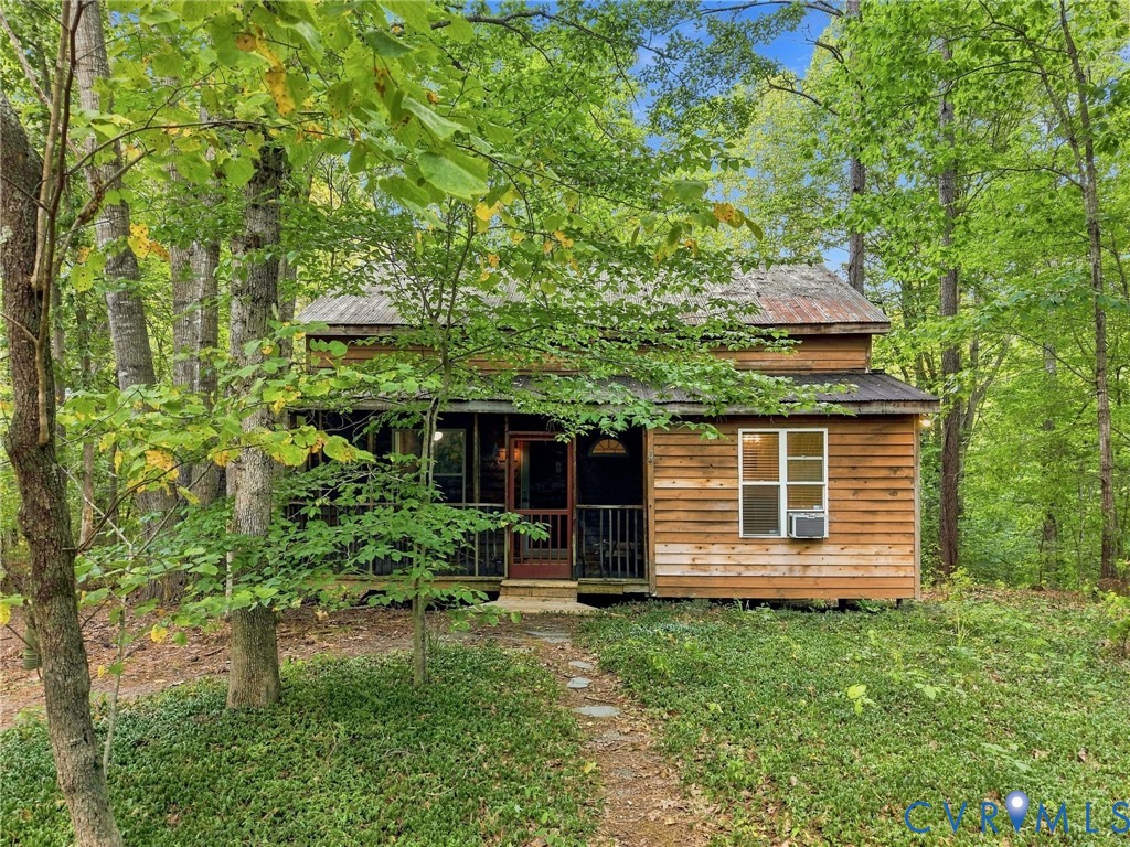 Wood-sided home with a covered porch and stone path, surrounded by trees.
