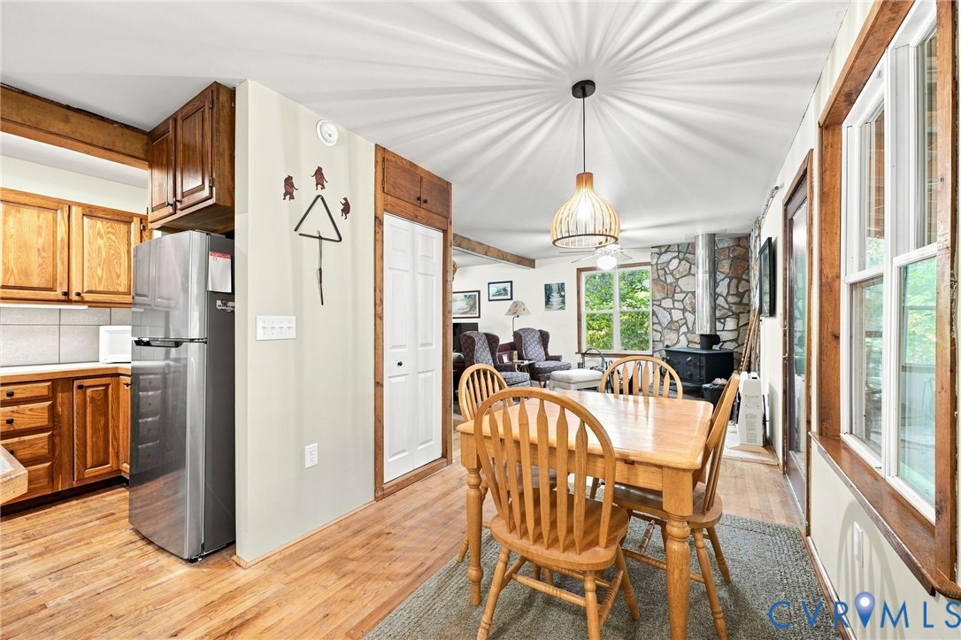 Open kitchen and dining area with wood cabinetry, a dining table, and a stone fireplace.