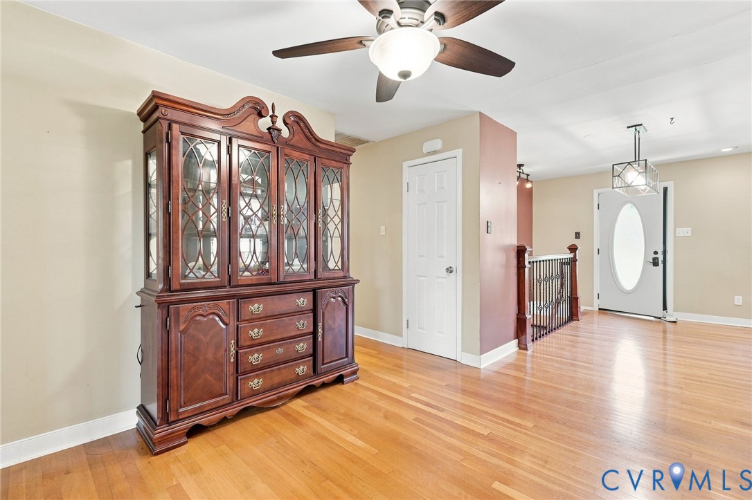 Entryway with hardwood floors, an ornate wooden china cabinet, and a white front door with oval glass.