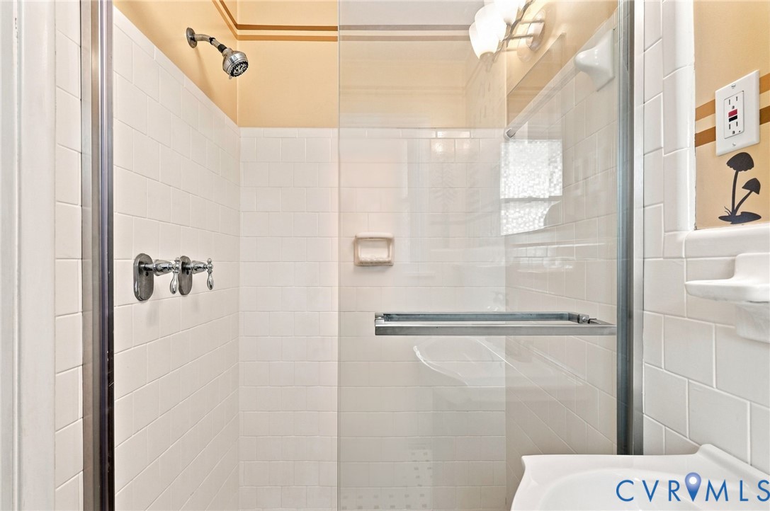 White-tiled shower with a glass enclosure, chrome fixtures, and a built-in soap dish.