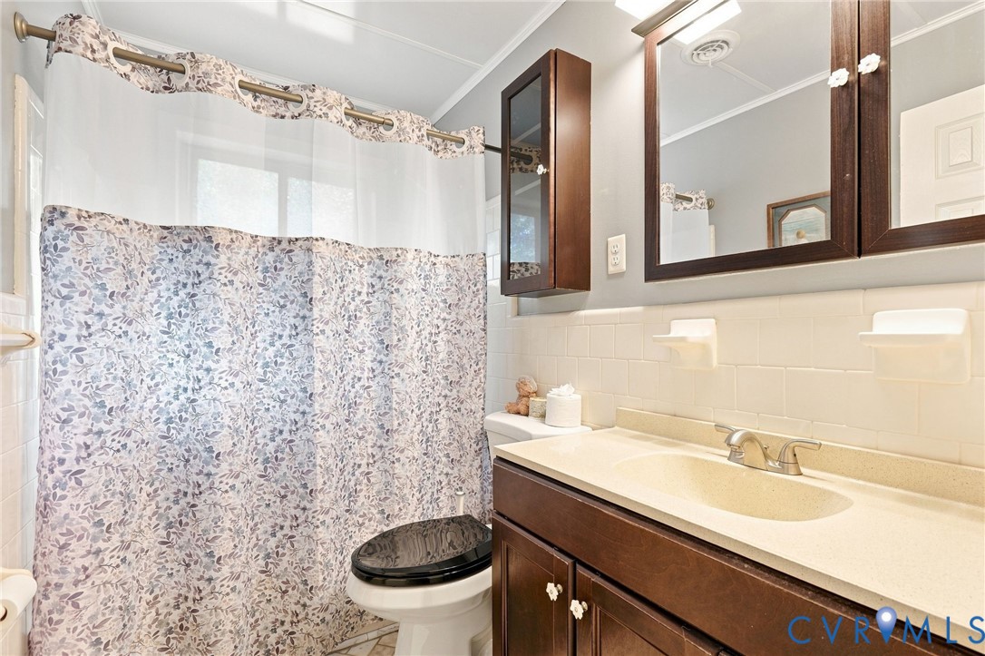 Bathroom with a floral shower curtain and dark wood vanity beneath a large mirror.