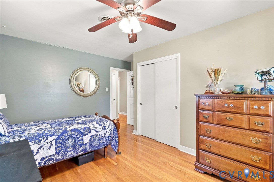 Bedroom with a blue-and-white patterned bed, hardwood floors, and a wooden dresser.