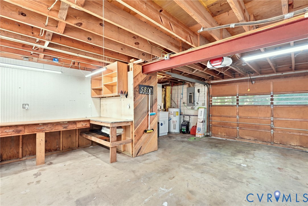 Garage with a built-in workbench and pegboard beneath exposed wooden ceiling framing.
