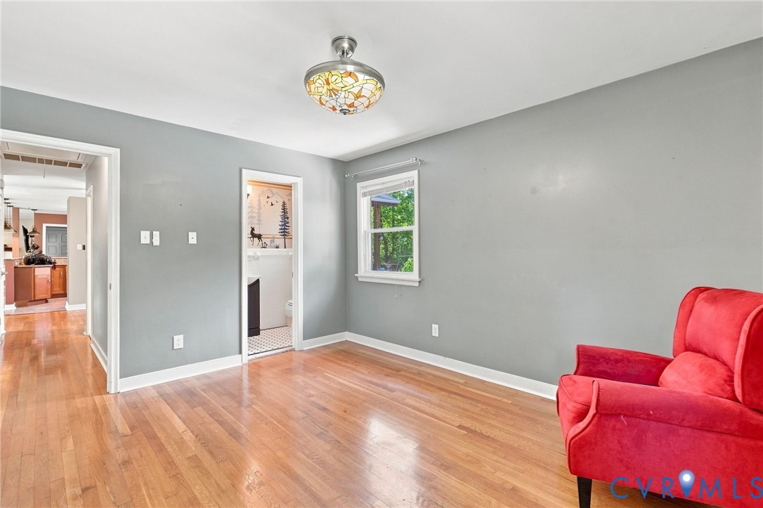Room with hardwood floors, gray walls, a stained-glass ceiling light, and a red armchair.