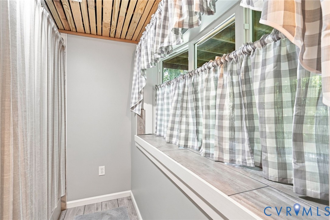 Sunroom with plaid curtains, a long tiled window sill, and a wood-slat ceiling.