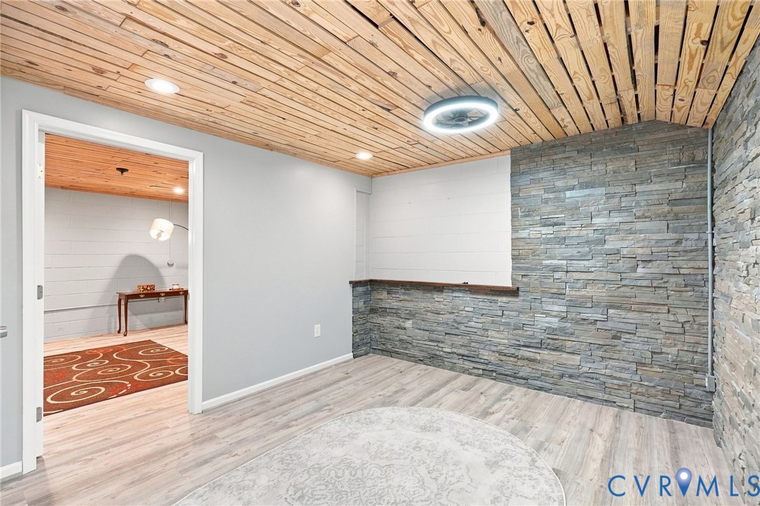 Room with a wood plank ceiling, stacked-stone wall, and short bar counter.