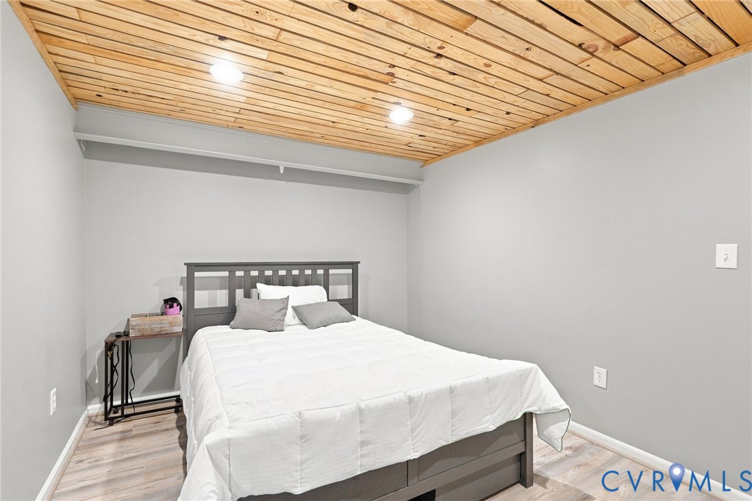 Bedroom with white bedding, gray walls, and a distinctive wood-plank ceiling.