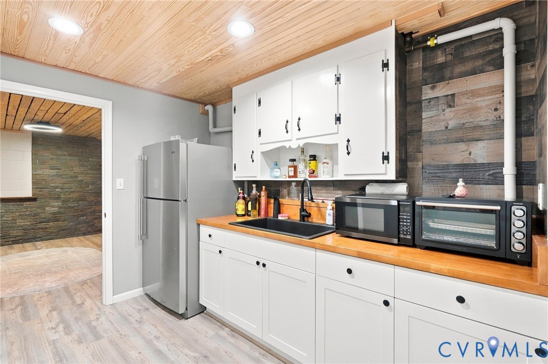 Kitchen with white cabinets, wood countertops, and a wood-plank ceiling.