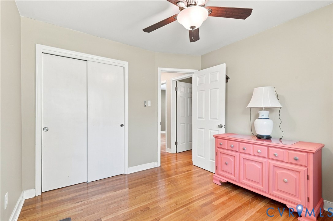 Bedroom with hardwood floors, a white sliding-door closet, and a pink dresser.