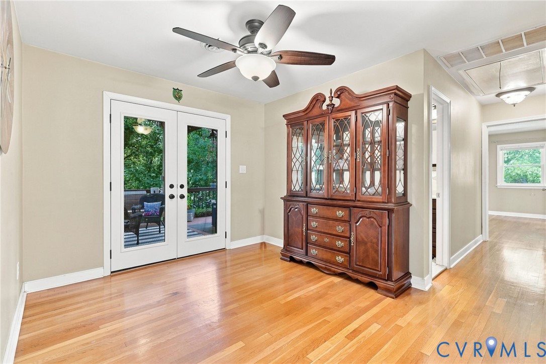 Dining room with hardwood floors, a carved china cabinet, and French doors opening to a deck.