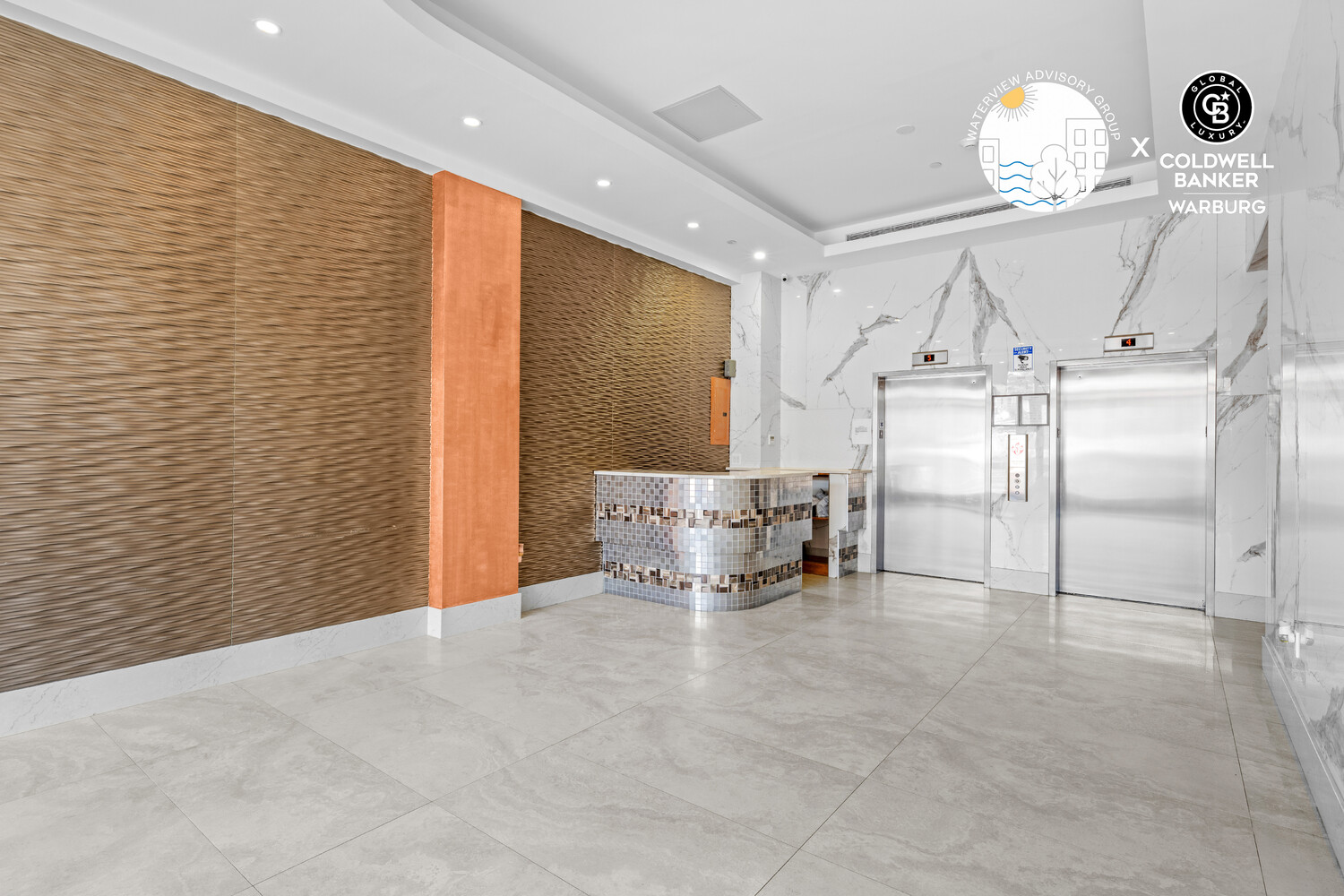 Building lobby with two elevators, a curved tiled reception desk, and a textured wood feature wall.