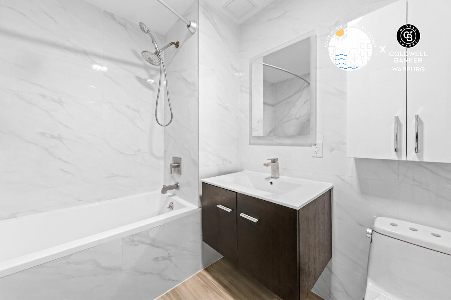 Bathroom with marble-look tile, glass shower panel, bathtub, and dark wood vanity.
