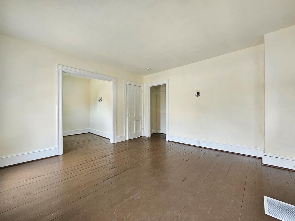 Empty room with brown hardwood floors and doorways to adjoining rooms.