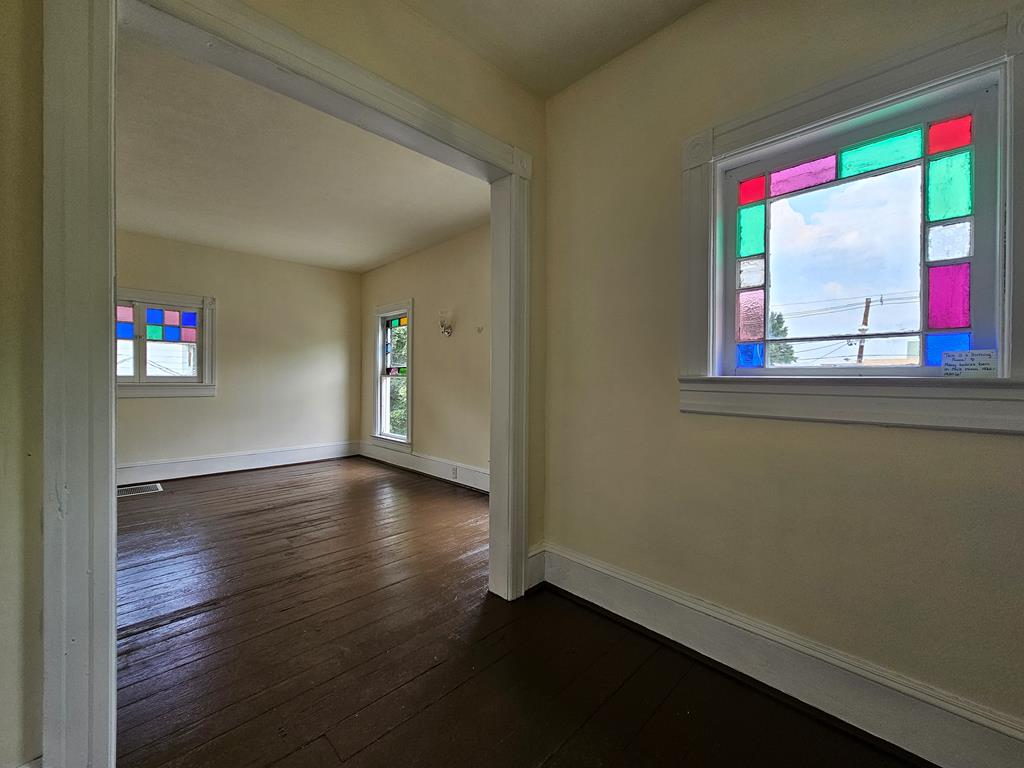 Empty room with dark wood floors and colorful stained-glass window panels.