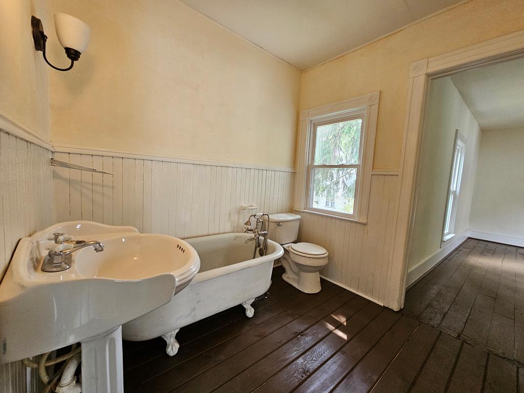Bathroom with a clawfoot tub, pedestal sink, and dark wood floors.