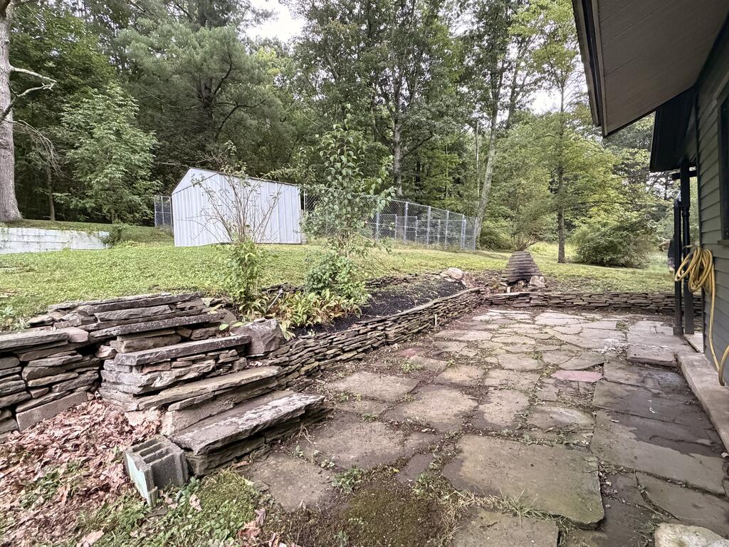 Stone patio beside the house, with retaining walls and a grassy yard beyond.