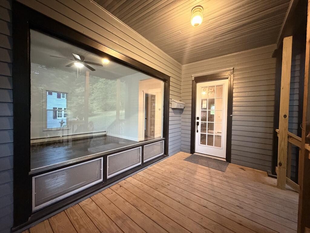 Covered porch with wooden decking, a large picture window, and a glass-paneled entry door.