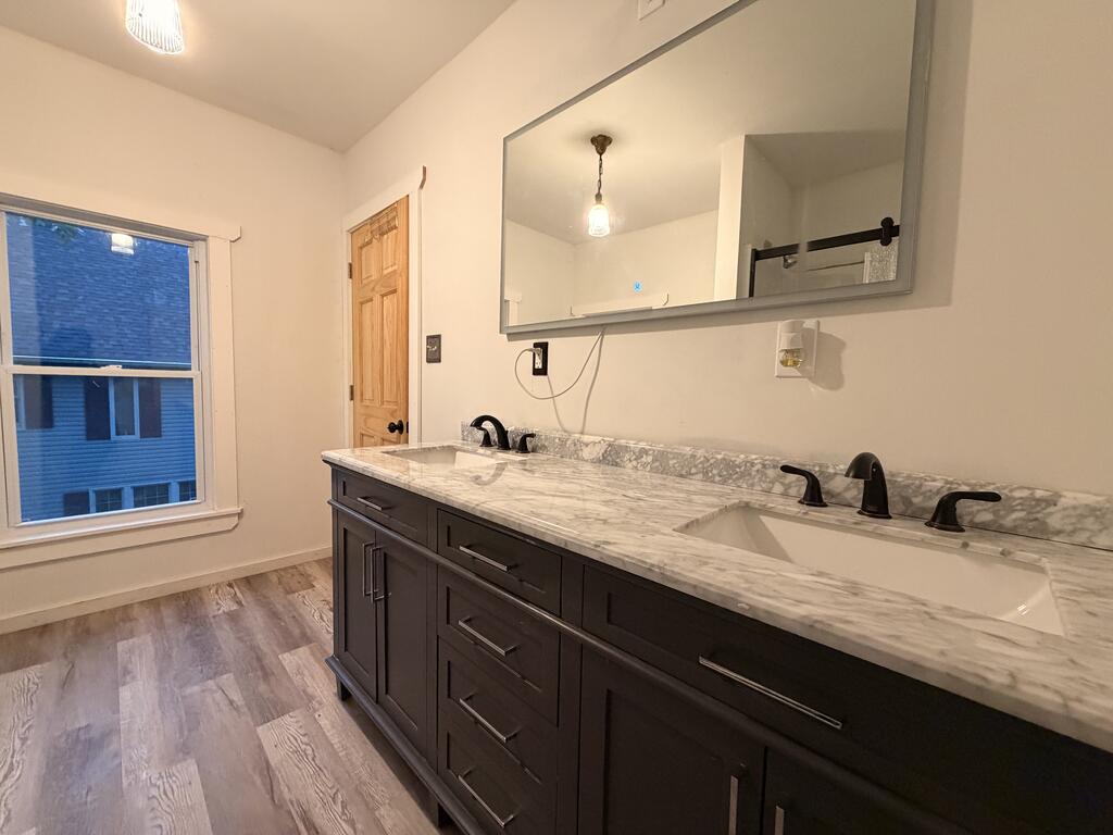 Bathroom with a dark double vanity, marble-pattern countertop, two sinks, and a large mirror.