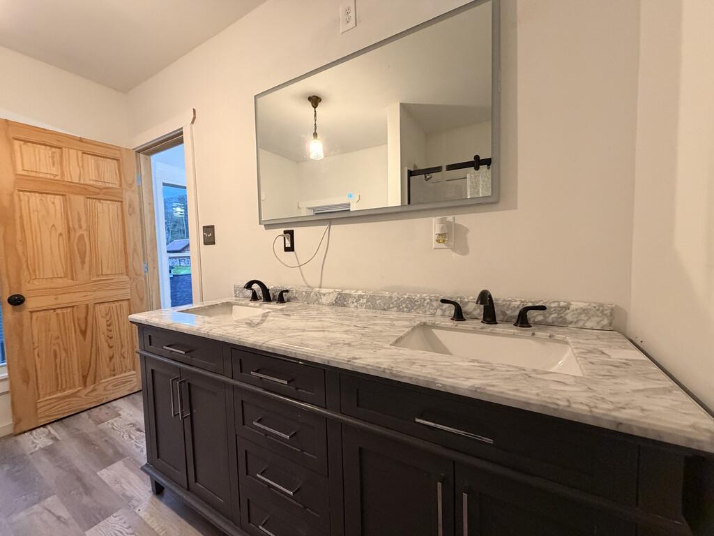 Bathroom with a dark double-sink vanity and marble-look countertop beneath a large mirror.