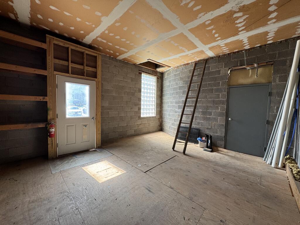 Unfinished garage with concrete block walls, exposed ceiling seams, and a glass-block window.