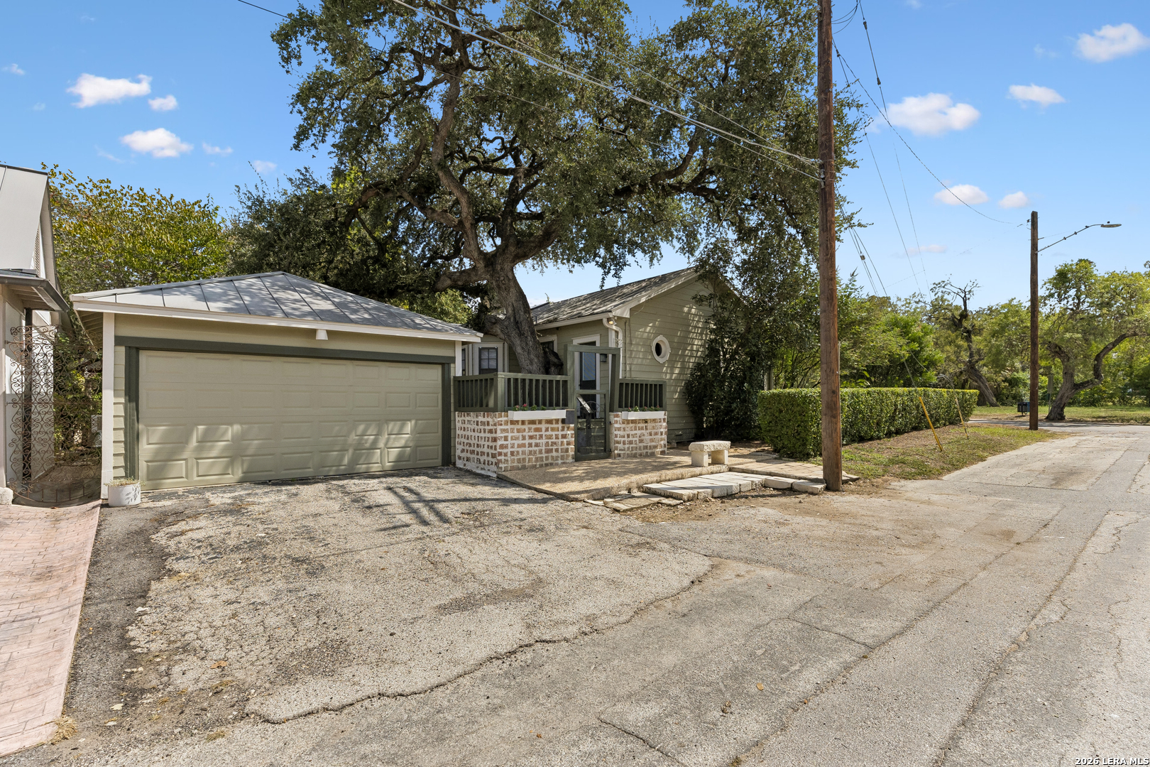 Single-story home with a two-car garage and porch beneath a large oak tree.