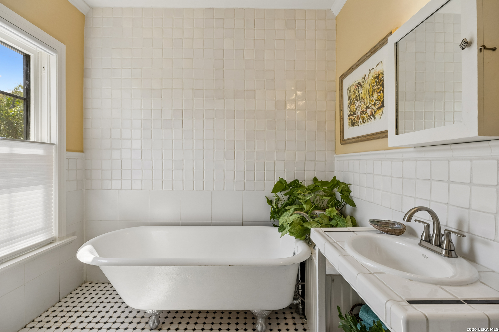 Bathroom with a white clawfoot tub, tiled vanity, and black-and-white hexagonal floor.