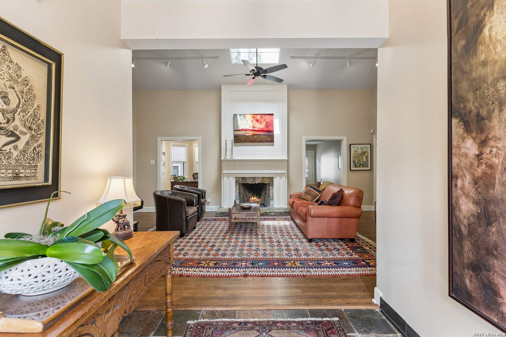 Living room with a fireplace, leather seating, patterned rugs, and a ceiling skylight.