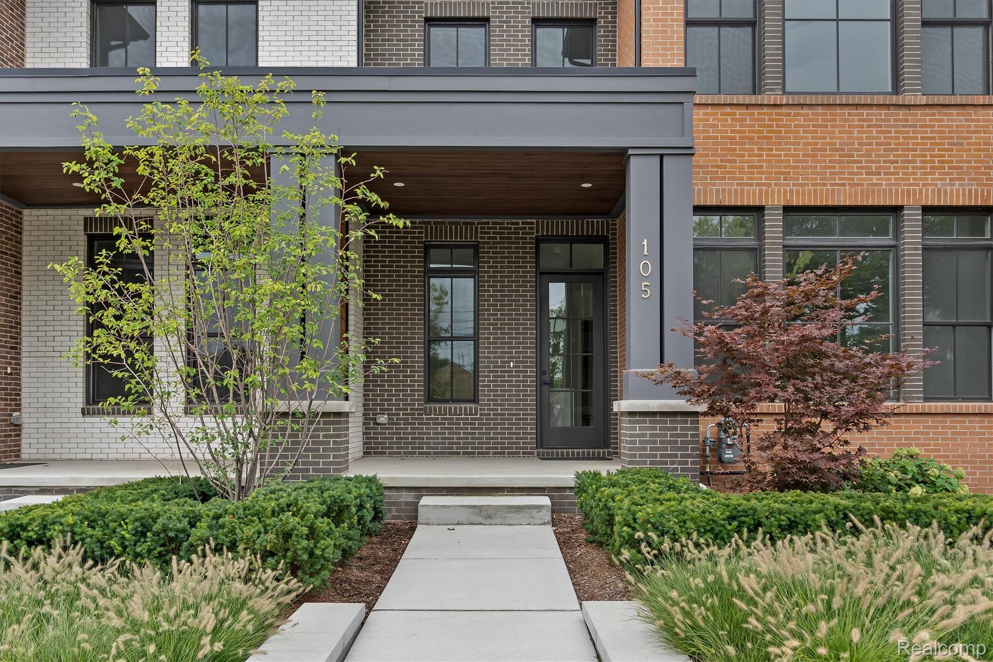 Modern brick residence entrance at 105, with a covered porch and landscaped walkway.