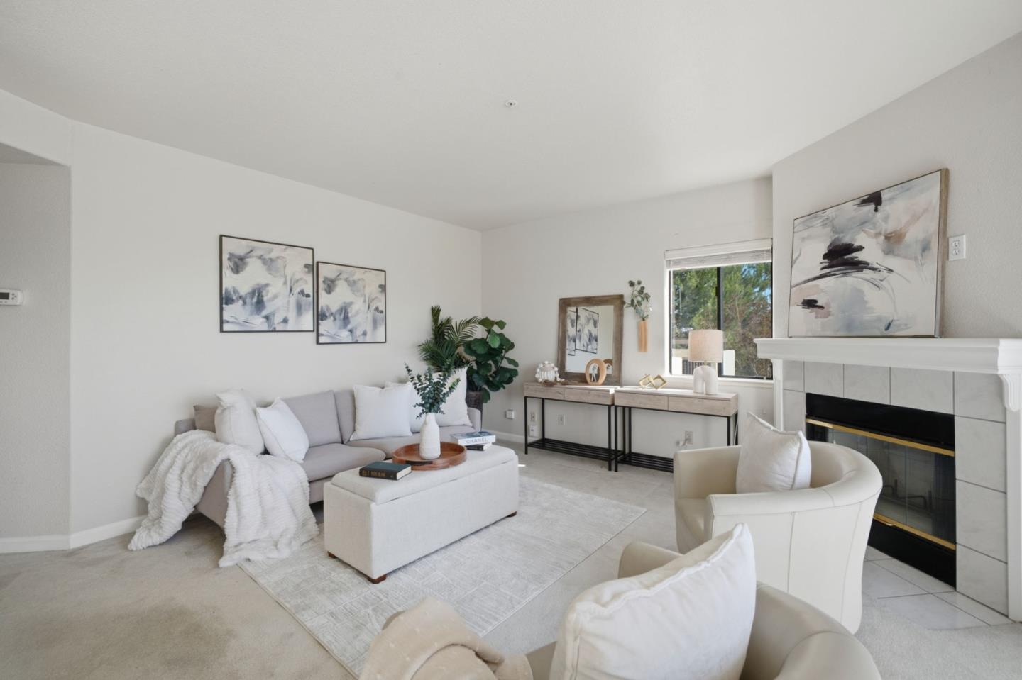 Staged living room with a gray sofa, white armchairs, and a tiled fireplace.