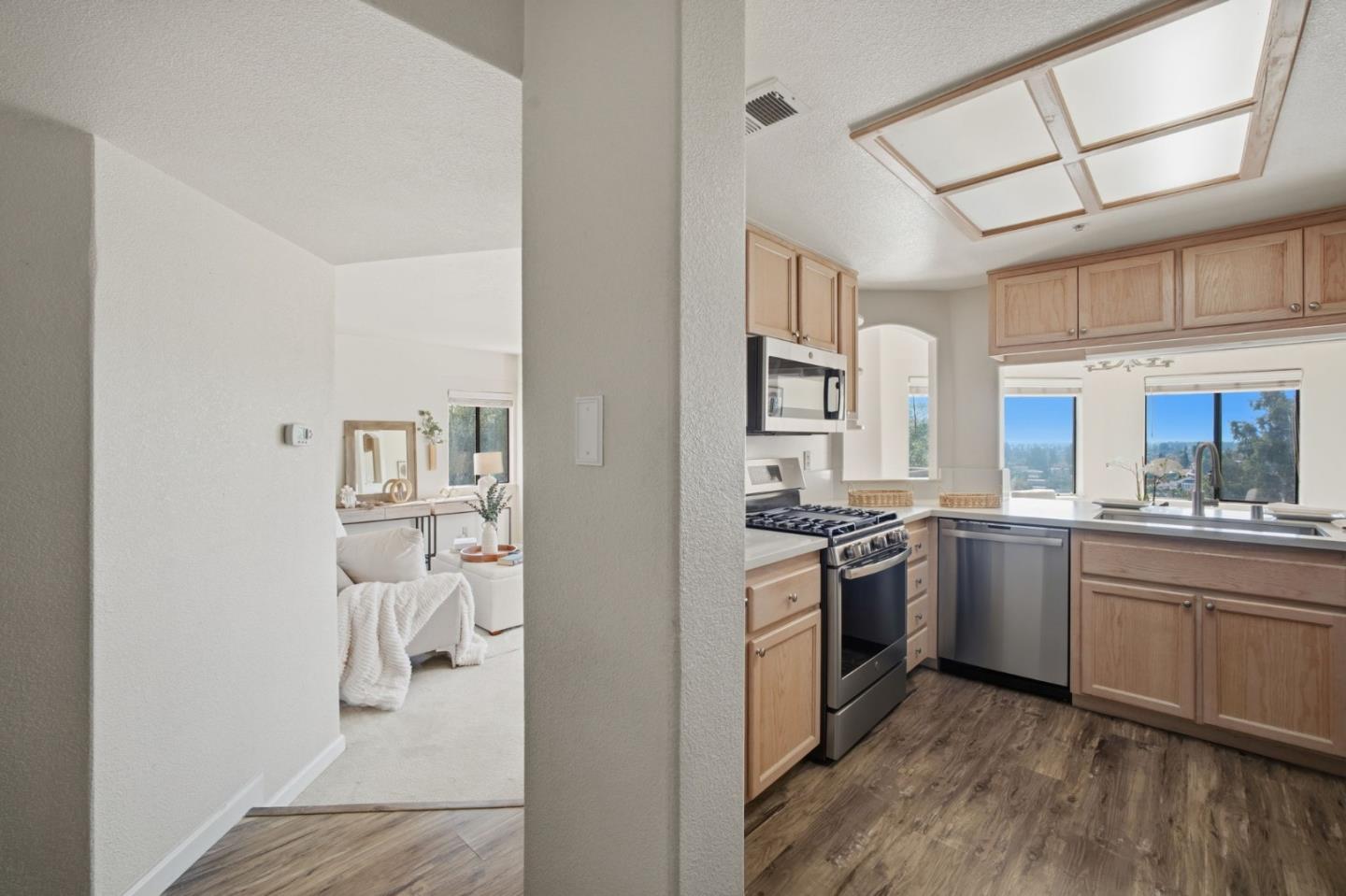 Bright kitchen with light wood cabinets, stainless steel appliances, and a large skylight.