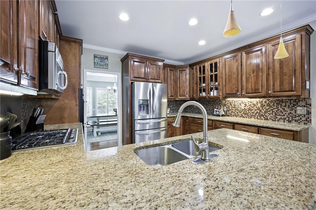Kitchen with dark wood cabinets, granite island, stainless steel appliances, and mosaic tile backsplash.