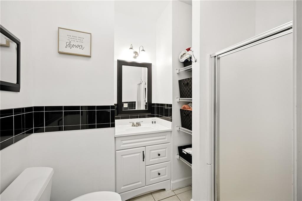 Bathroom with a white vanity, black tile accent band, and sliding shower door.