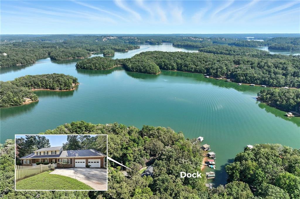 Aerial view of a wooded lake and docks, with an inset showing a two-story brick house.